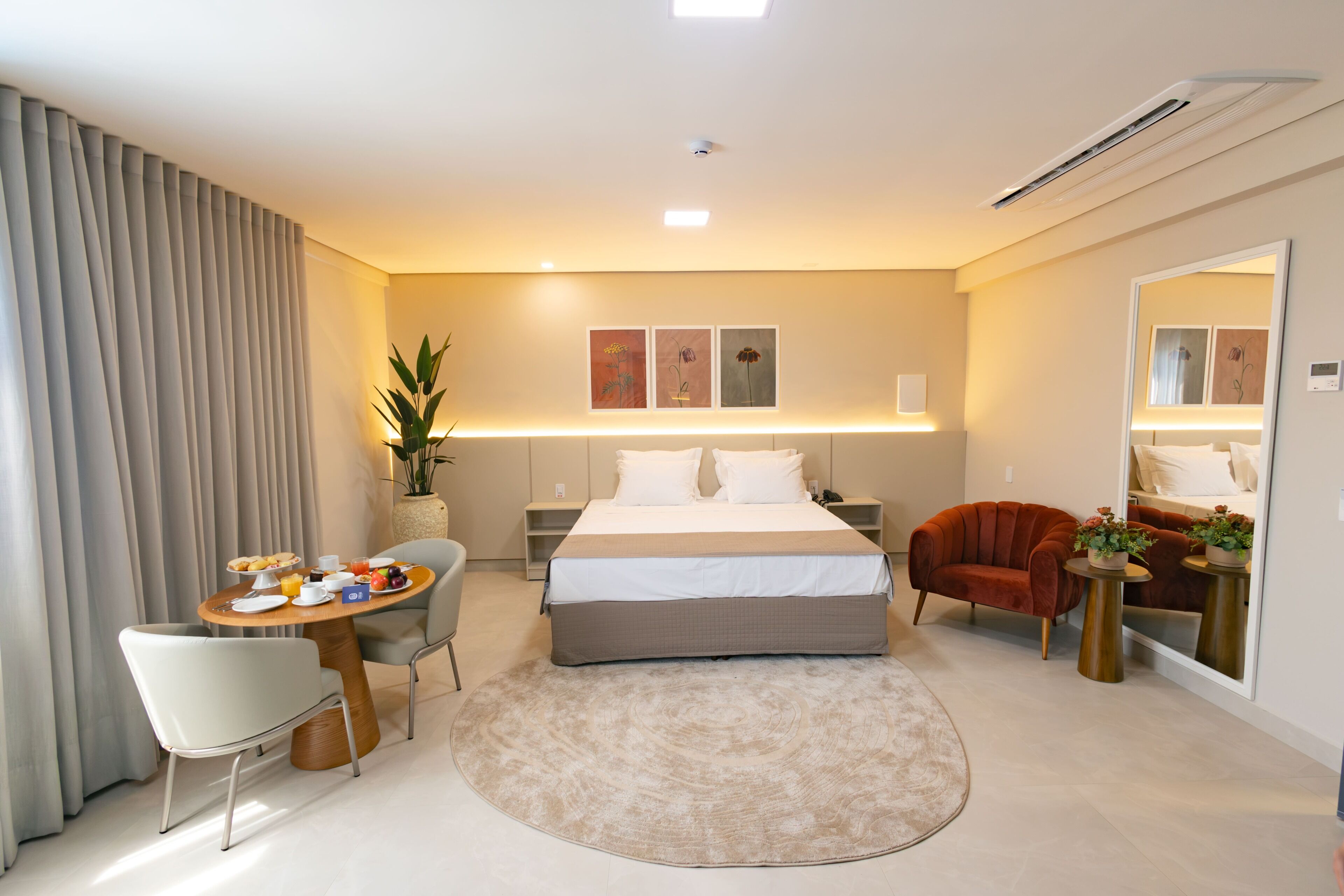 Et hotelværelse med seng, natbord, stol, skrivebord og et spejl.