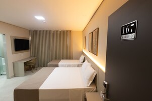 Habitación de hotel con dos camas, un escritorio, un televisor y un cartel en la pared que indica el número de habitación 167.