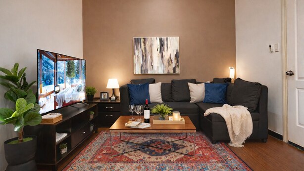 A living room with a sofa, coffee table, TV, and decorative items. - New! 2BR w/ City Views in Makati & Fast Wi-Fi! (Makati)