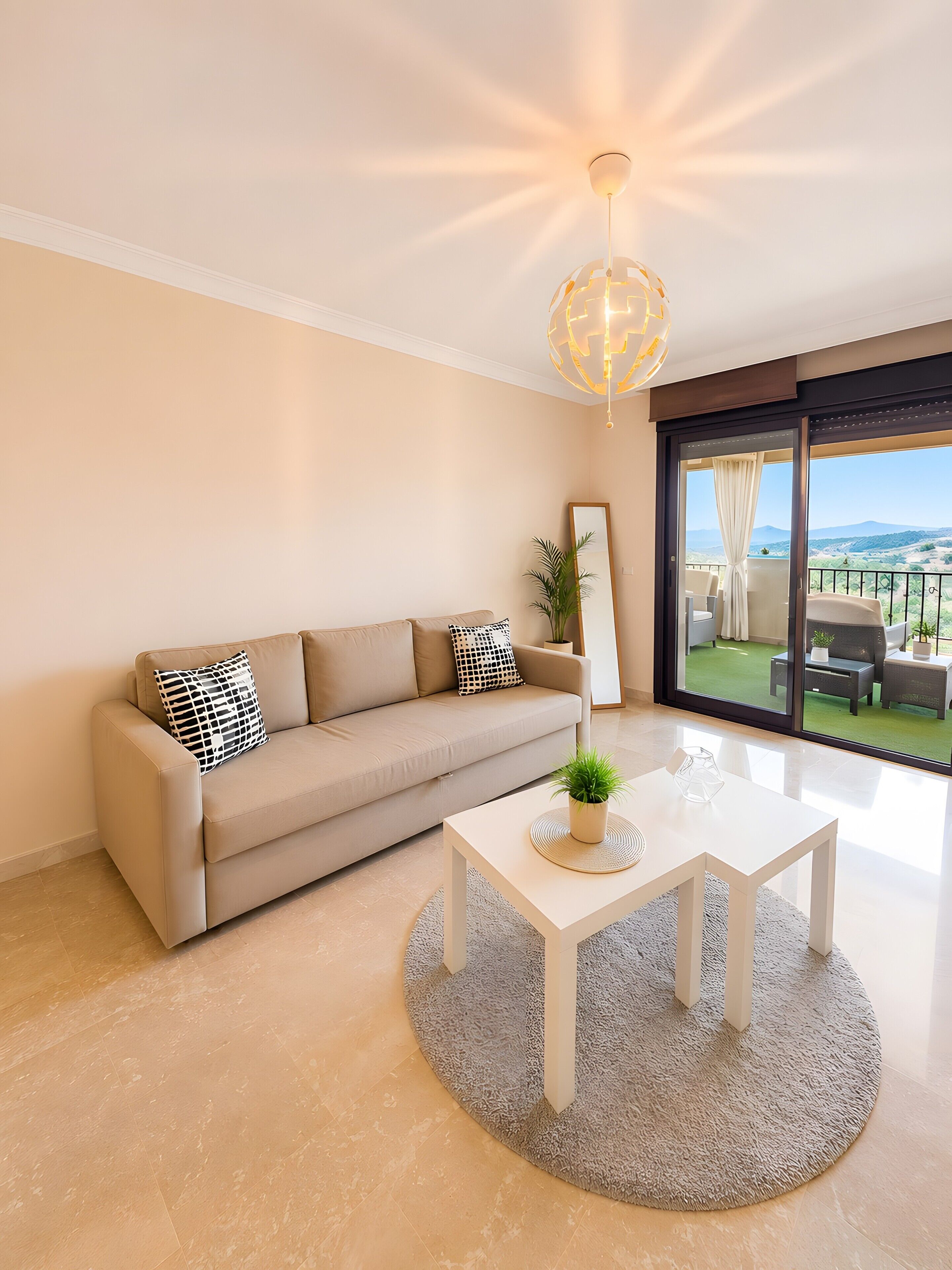 A modern living room with a sofa, a coffee table, and a view through a glass door.