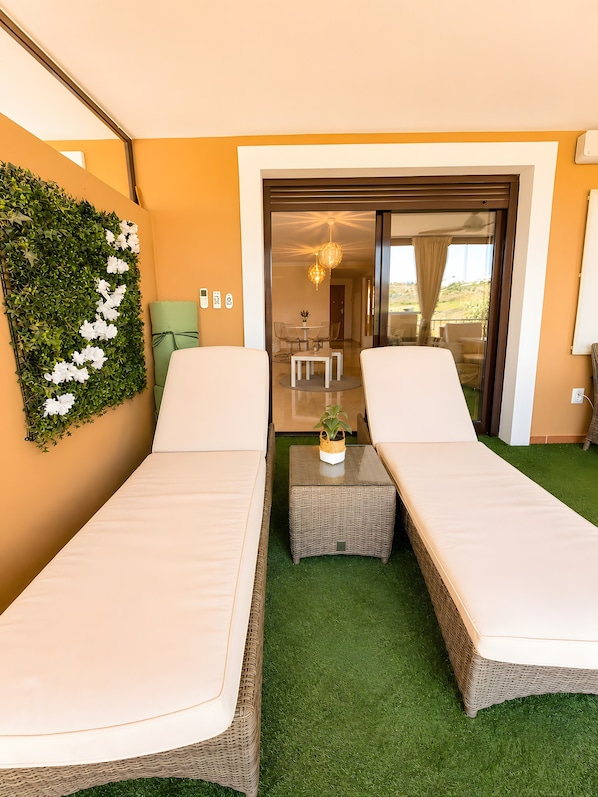 A room with two beds, a small table, and a green wall with white flowers.