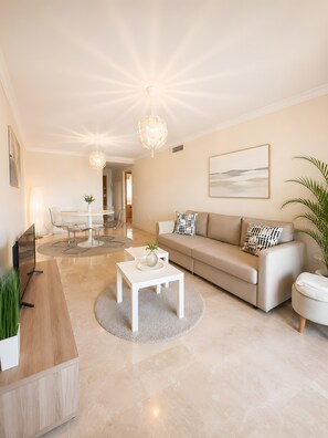 A modern living room with a sofa, coffee table, and a dining area with chairs and a table.