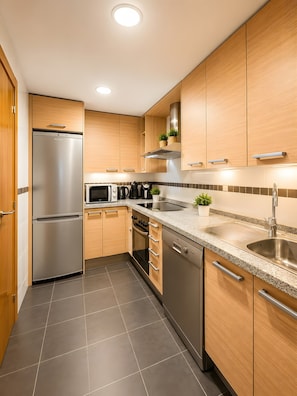 A modern kitchen with stainless steel appliances, wooden cabinets, and a granite countertop. - Golf & Mountain: Private Terrace at Calanova Golf (Las Lagunas)