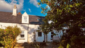 A white building with a sloped roof, a chimney, and a small window. - Cosy Cottage Retreat in Edinbane (Skeabost)