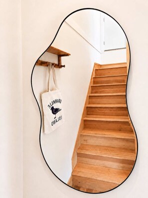 Eine Holztreppe, eine weiße Wand und ein Spiegel, der die Treppe reflektiert.