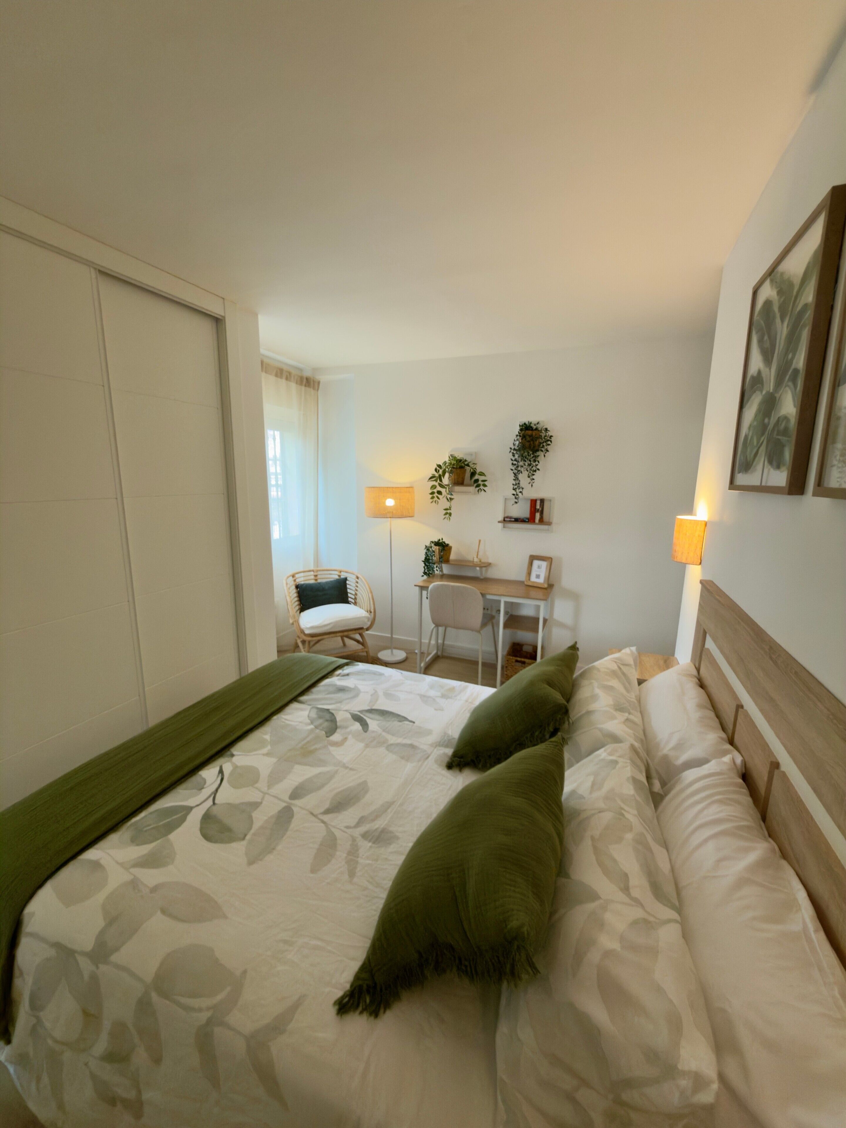 Et hotelværelse med seng, skrivebord, stol og lampe.