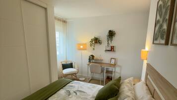 Et hotelværelse med seng, skrivebord, stol og lampe.