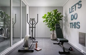 A home gym with exercise equipment, a potted plant, and motivational wall art. - Santiago Parque Ohiggins - Domus Travels (Santiago)