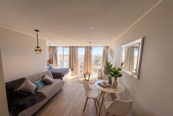 A modern living room with a sofa, dining table, chairs, a small table, and a potted plant. - Santiago Parque Ohiggins - Domus Travels (Santiago)