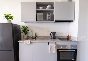 A modern kitchen with a built-in microwave, oven, and stainless steel refrigerator. - Santiago Parque Ohiggins - Domus Travels (Santiago)