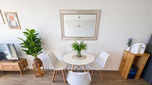 Un comedor con una mesa redonda, cuatro sillas, una planta en maceta, un espejo y un aparador de madera.