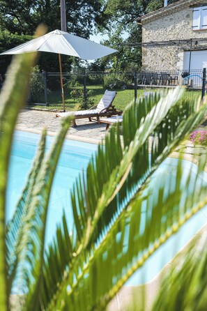 A swimming pool with a lounge chair and umbrella, surrounded by a stone building and greenery. - Maison Bordeneuve: Sharing the Charm of the Gers (Préneron)