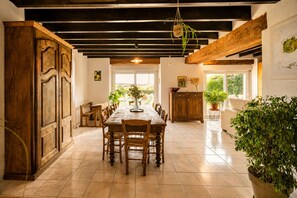A spacious dining area with a long wooden table, chairs, and a wooden cabinet.