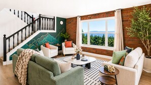 A living room with a staircase, a view of greenery, and a brick wall. - Luxury Retreat| Theater, Golf, Spa, Firepit & Views (Ahwahnee)
