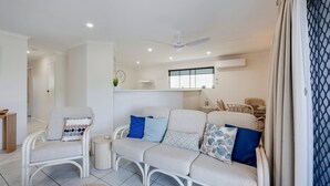 Un salon moderne avec un canapé, des fauteuils, une petite table et un ventilateur de plafond.