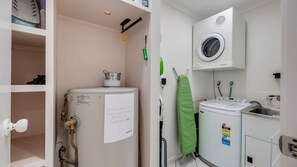 A compact laundry room with a washing machine, a dryer, and a water heater. - 1/20 Bauer Street Bargara (Bargara)