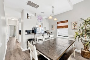 A modern kitchen with granite countertops, a stainless steel refrigerator, and white cabinetry. - Dolphin View Duplex A Beachfront | Pet Friendly (Gulf Shores)