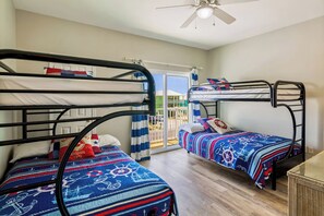 Une chambre avec deux lits superposés, un ventilateur de plafond et une vue sur un balcon.