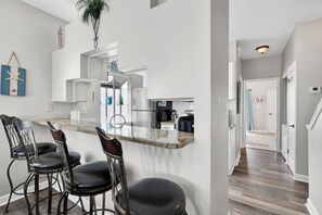 Een moderne keuken met een bar, barkrukken en een uitzicht op de woonkamer.