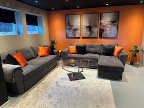 Ein modernes Wohnzimmer mit einer Eckcouch, einem Glastisch und abstrakter Wandkunst.