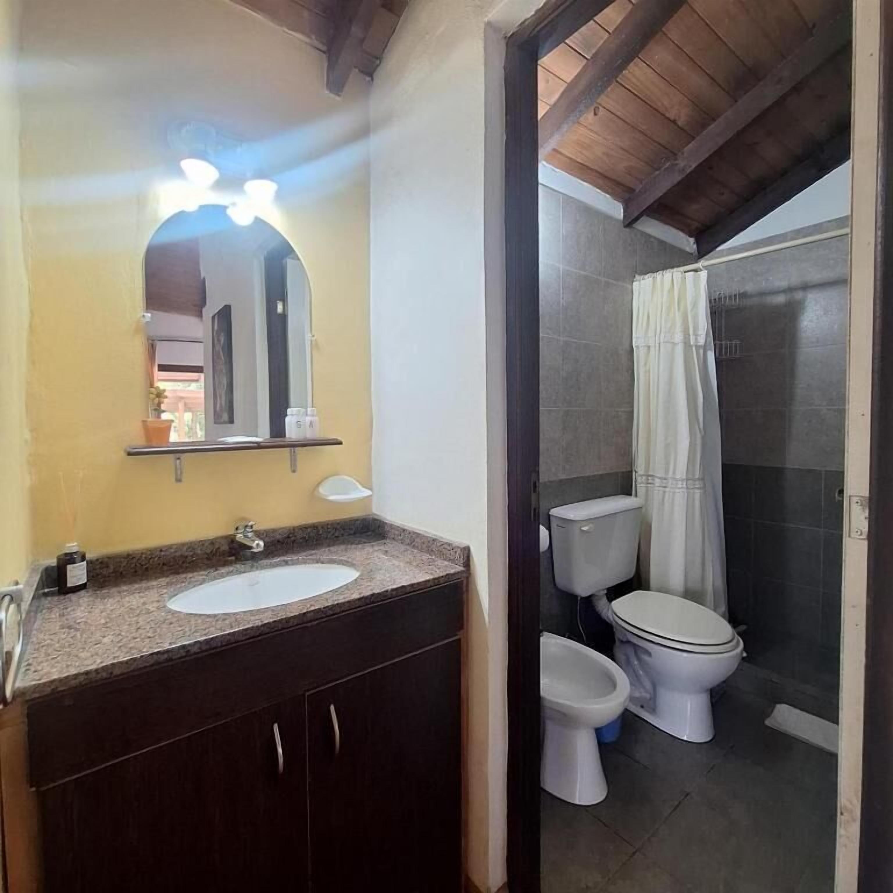 Un baño con lavamanos, espejo y dos inodoros.