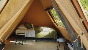 Una tenda con un letto, uno sgabello e un tavolo.