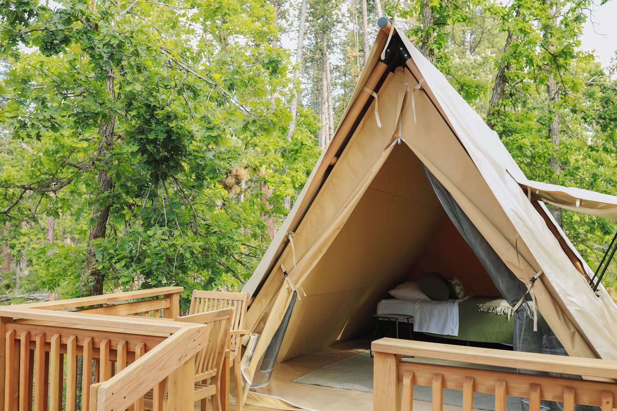A tent with a wooden deck and a bed inside.
