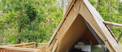 A tent with a wooden deck and a bed inside.