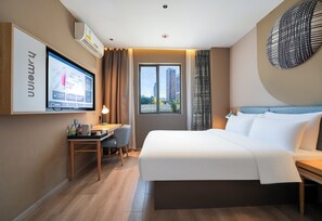 Quarto de hotel com cama, escrivaninha, cadeira, televisão e vista para edifícios.