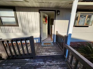 Eine Holztreppe führt zu einer Tür mit einer Fußmatte, auf der 'HOME' steht.