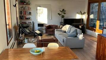 A living room with a sofa, a coffee table, a TV, and a bookshelf.