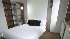 Ein Schlafzimmer mit einem Bett, einem Kleiderschrank und einem Regal mit Tassen.