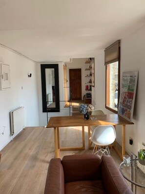 A modern living room with a wooden dining table, a brown leather sofa, and a glass coffee table. - Modern East London (terrace) (Greater London)