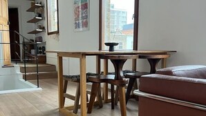Ein modernes Wohnzimmer mit einem Holzesstisch, einem braunen Sofa und einer Treppe, die zu einer oberen Etage führt.