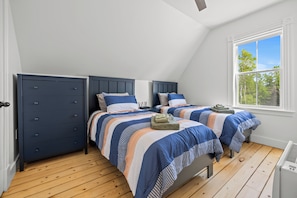 A bedroom with two beds, a dresser, and a window with a view of trees. - Cavendish Gables Cottage (Green Gables)