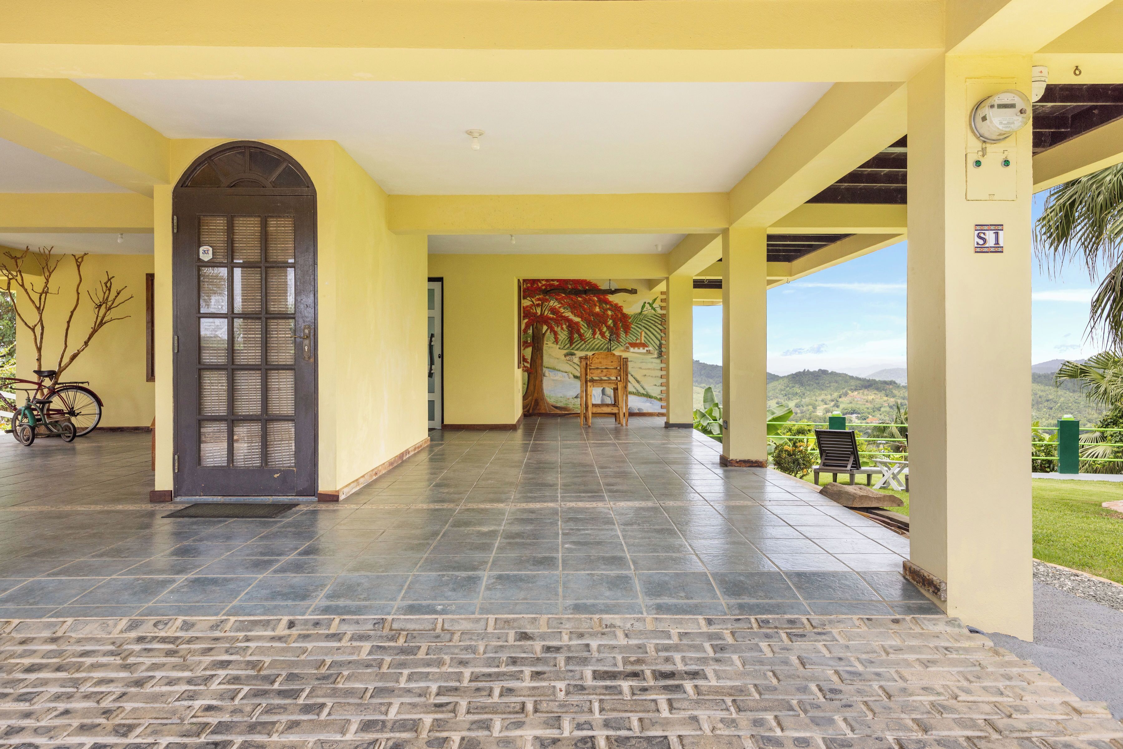 Un acceso cubierto con suelo de baldosas, una puerta y vistas al exterior.