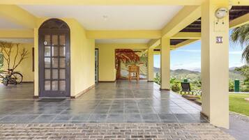 Un acceso cubierto con suelo de baldosas, una puerta y vistas al exterior.