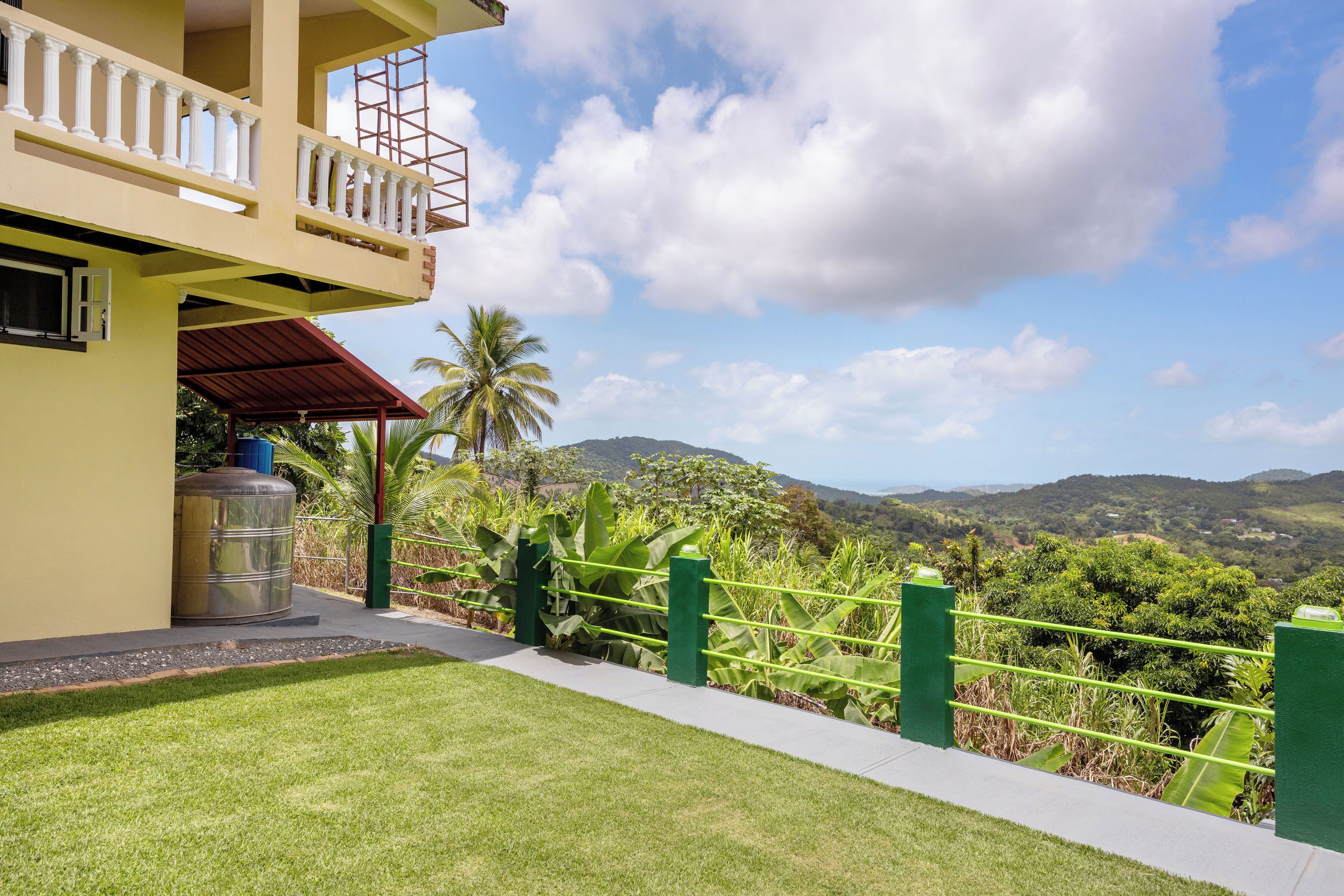 A building with a balcony, a green fence, and a view of mountains.