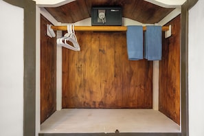 Quarto com porta de madeira, porta-toalhas e um pequeno banquinho de madeira.