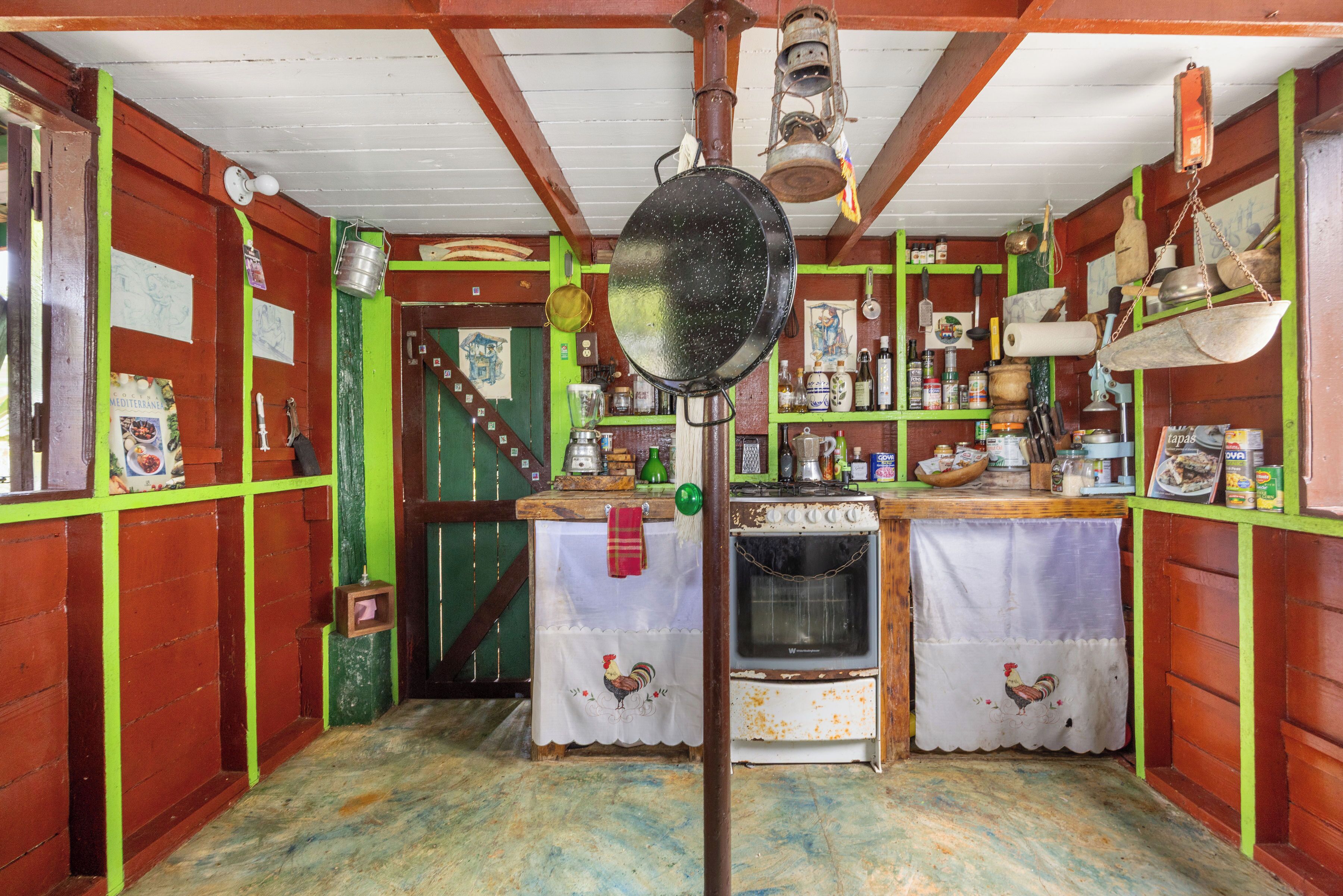 Una cocina rústica con paredes de madera, estufa y diferentes utensilios de cocina.