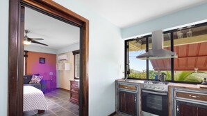 Une cuisine équipée d’une cuisinière, d’un four et d’une fenêtre donnant sur un jardin.