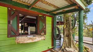 Une cuisine extérieure rustique, dotée d’un plan de travail en bois, d’un évier et d’un tuyau d’arrosage.