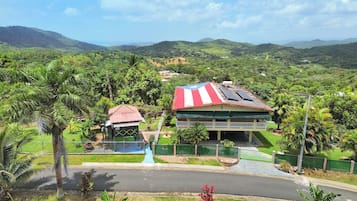 A hotel with a red and white striped roof, surrounded by lush greenery and hills.