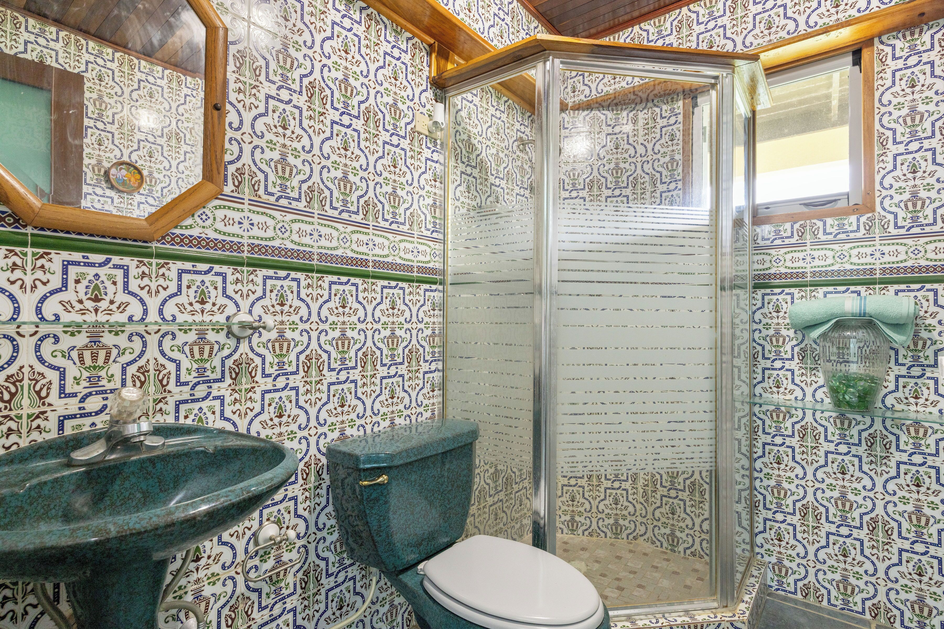 Un baño con lavamanos, inodoro y ducha con azulejos decorados.