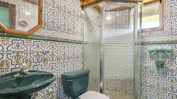 Un baño con lavamanos, inodoro y ducha con azulejos decorados.