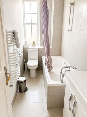A bathroom with a toilet, bathtub, shower, and radiator. - 2-Bedroom Home with FREE Parking near Sydenham Station (Greater London)