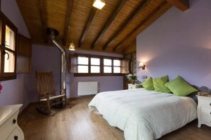 A bedroom with a wooden ceiling, a bed with green pillows, a nightstand, a chair, and a window with a view. - The LLananzanes Lookout - Rural Asturias - HOUSE I (Conforcos (Aller))