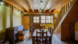 A cozy cabin interior with a dining area, a fireplace, and a staircase. - The LLananzanes Lookout—Asturias Rural—CASA II (Conforcos (Aller))