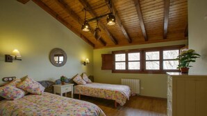 A bedroom with two beds, wooden ceiling beams, a window with shutters, and a potted plant. - The LLananzanes Lookout—Asturias Rural—CASA II (Conforcos (Aller))