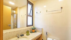 Ein modernes Badezimmer mit großem Spiegel, Dusche, Waschbecken und Handtuchhalter.